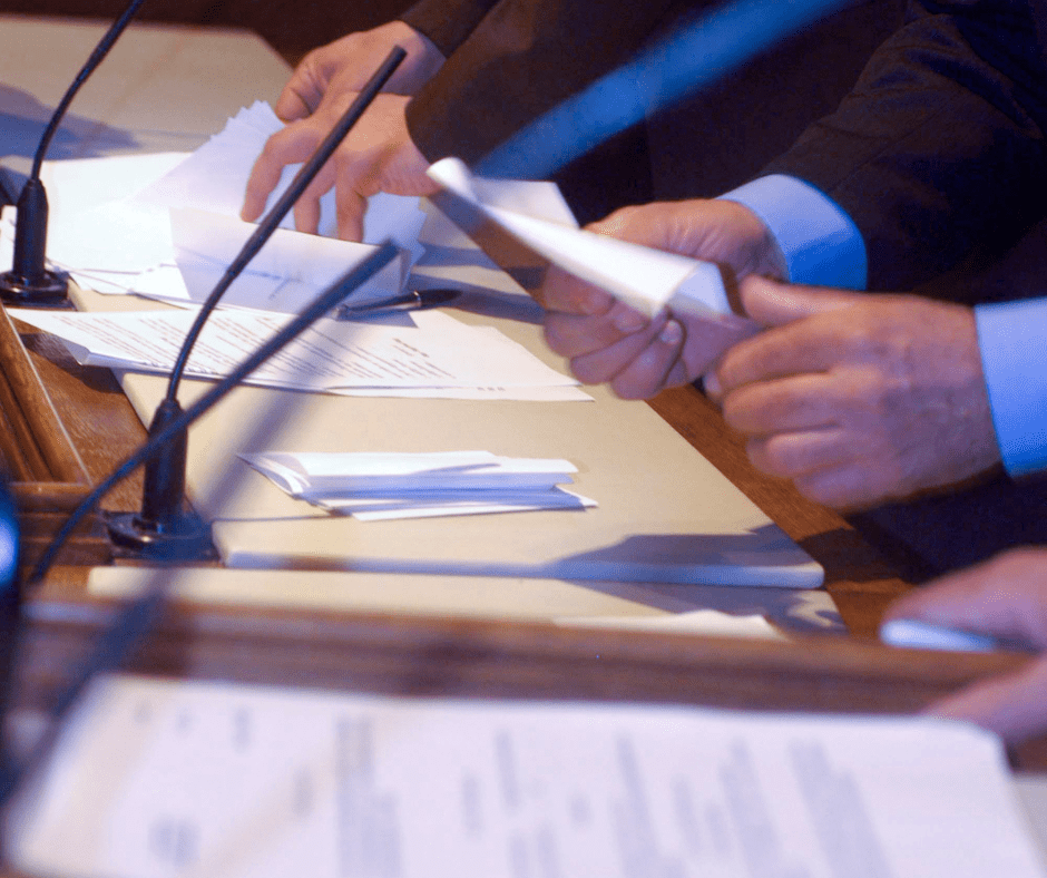 men holding papers in front of microphone