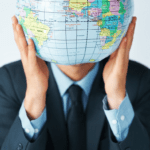 man in suit holding globe in front of his face