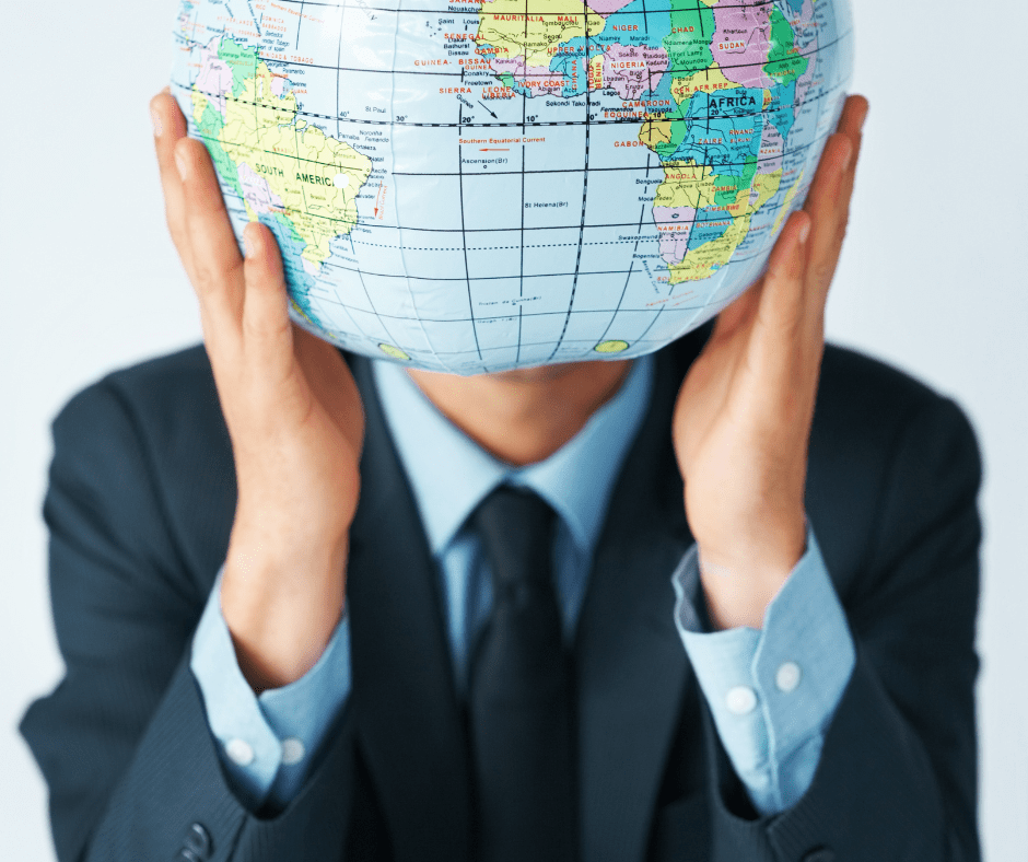 man in suit holding globe in front of his face